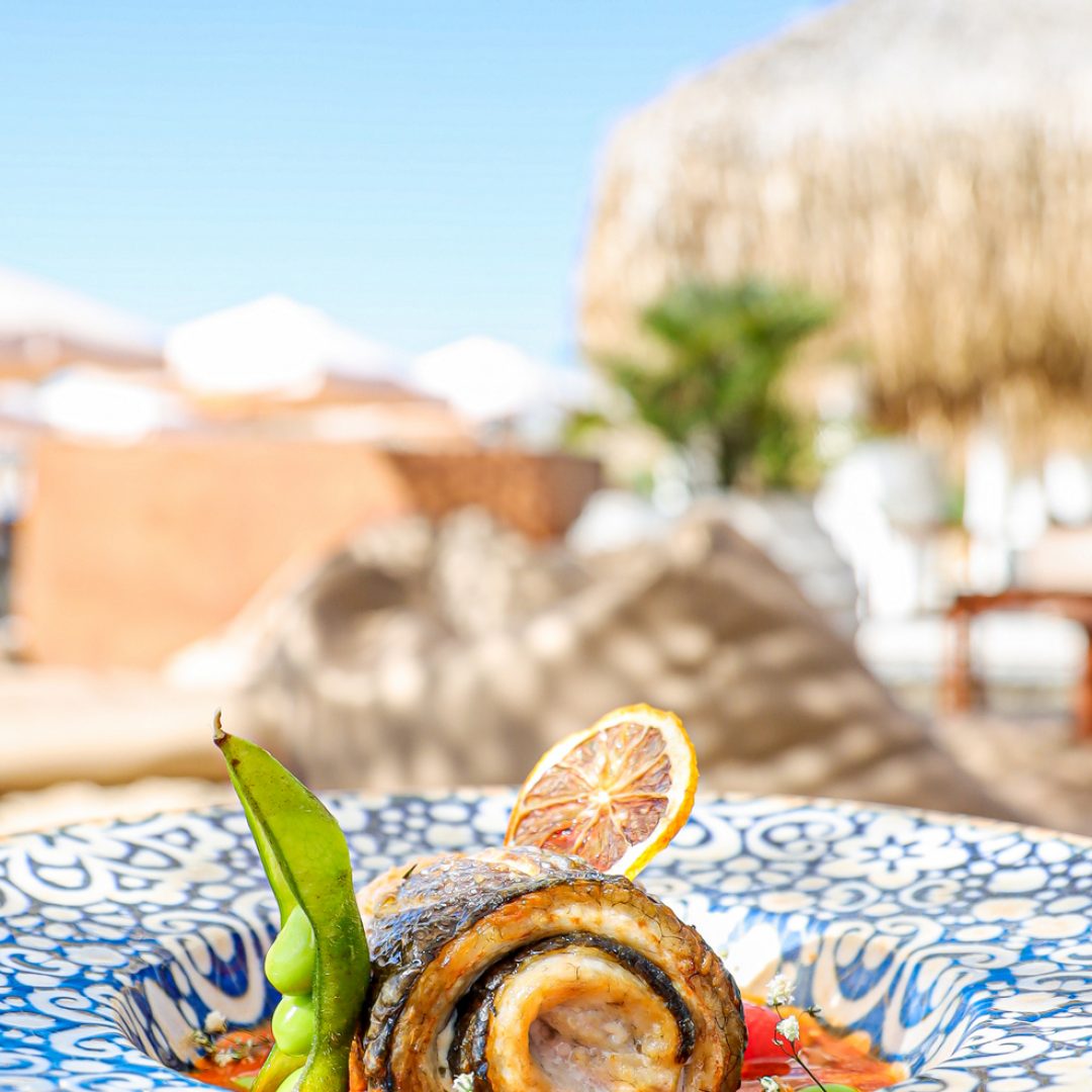A vertical shot of a gourmet fish dish at a beachside restaurant
